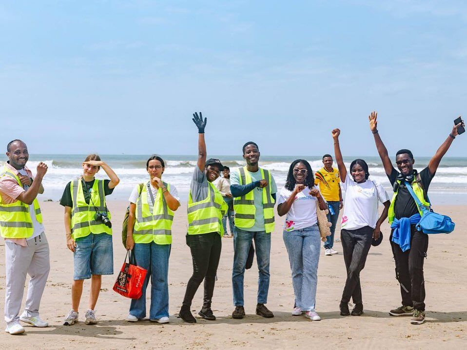 Asaase Yaa volunteers in high-visibility vests celebrating on the beach after a clean-up
